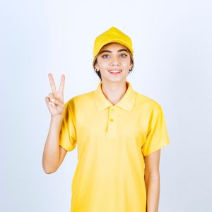 delivery-woman-yellow-uniform-standing-showing-victory-sign_144627-68900