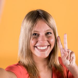 portrait-smiling-young-woman-showing-peace-sign_23-2148188447