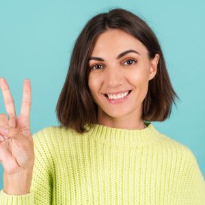 young-woman-light-green-sweater-smiling-shows-v-sign_343596-7183